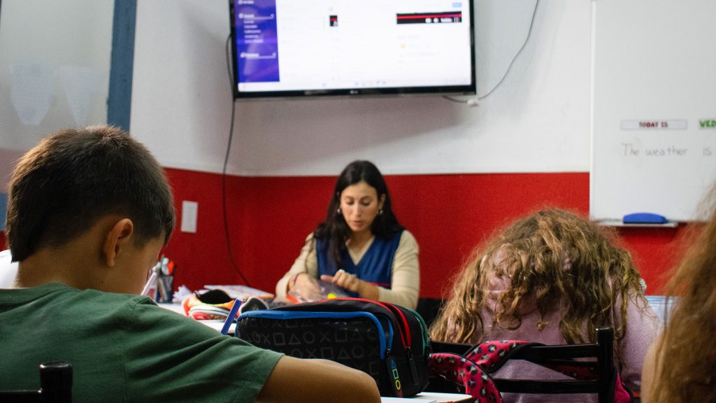Clase de inglés en primaria con maestra y recursos audiovisuales