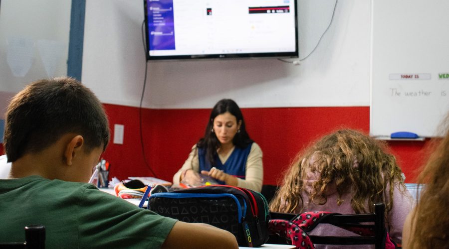 Clase de inglés en primaria con maestra y recursos audiovisuales